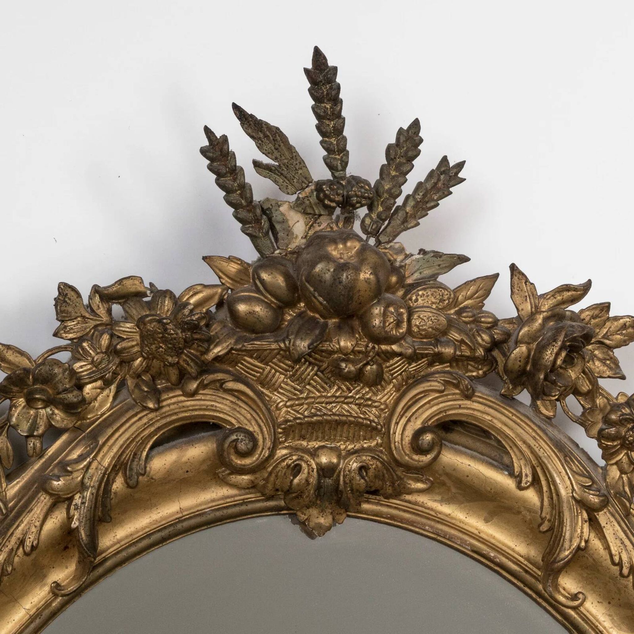 French 19th-century oval mirror in gold leaf with a pediment.