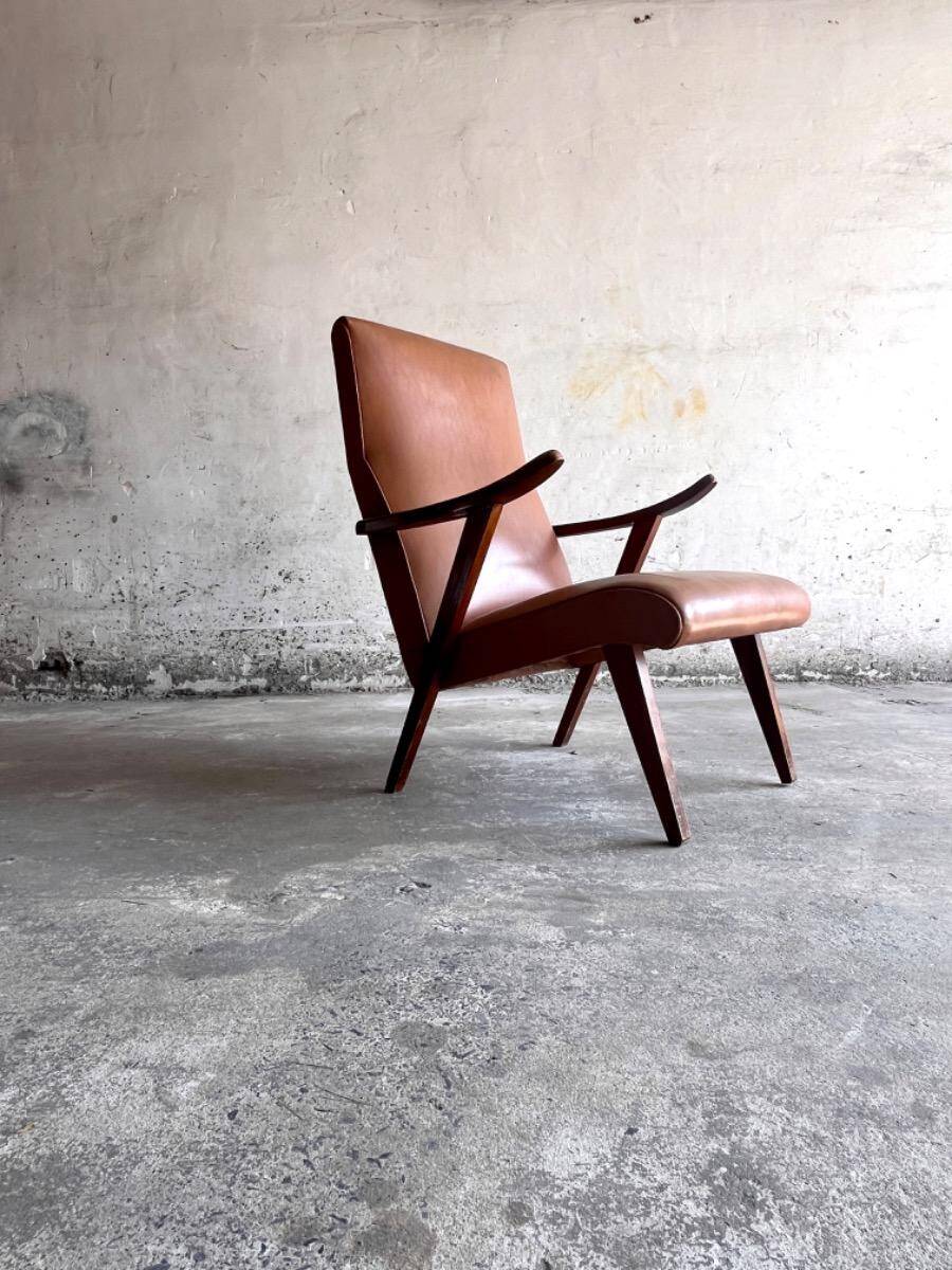 Vintage armchair from the 1950s in cognac leather and dark wood — modernist lounge chair.