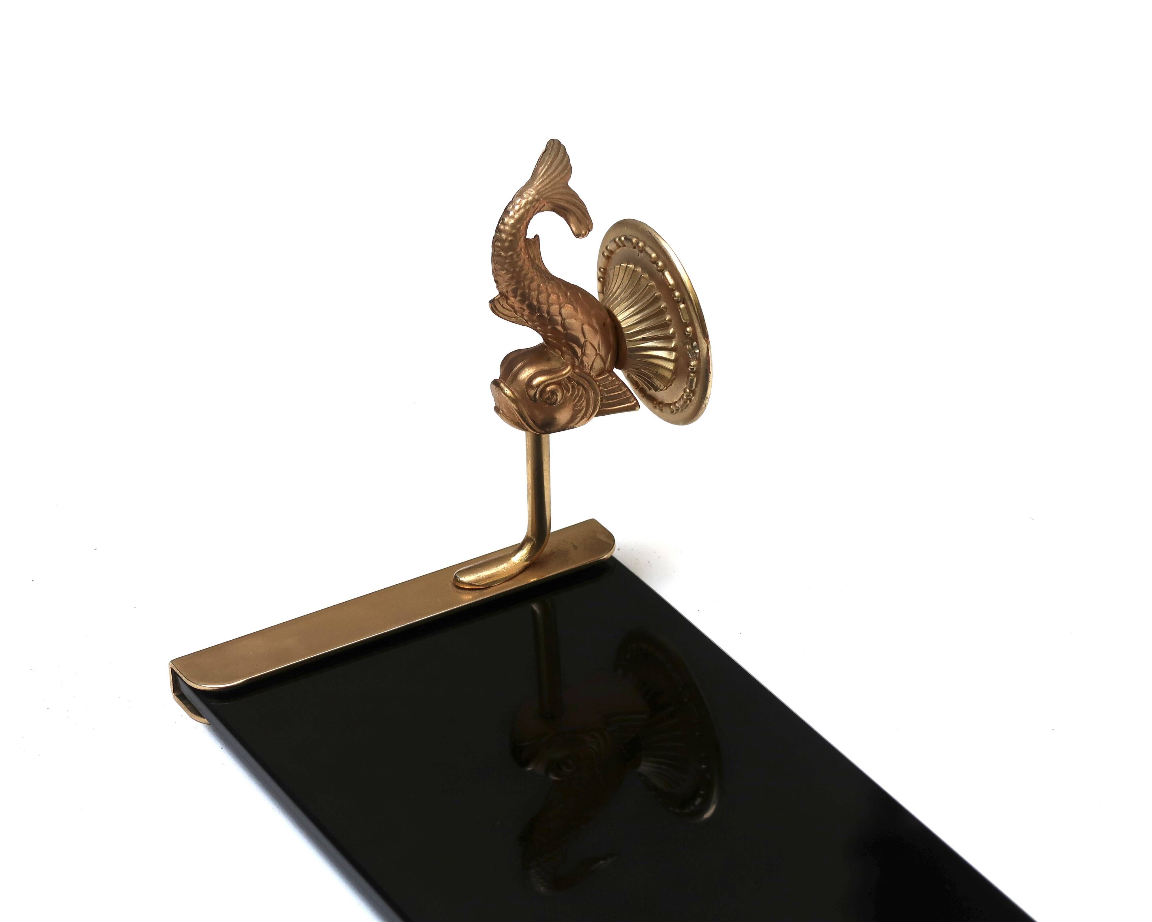 Wall shelf in gold metal and black glass adorned with fish.