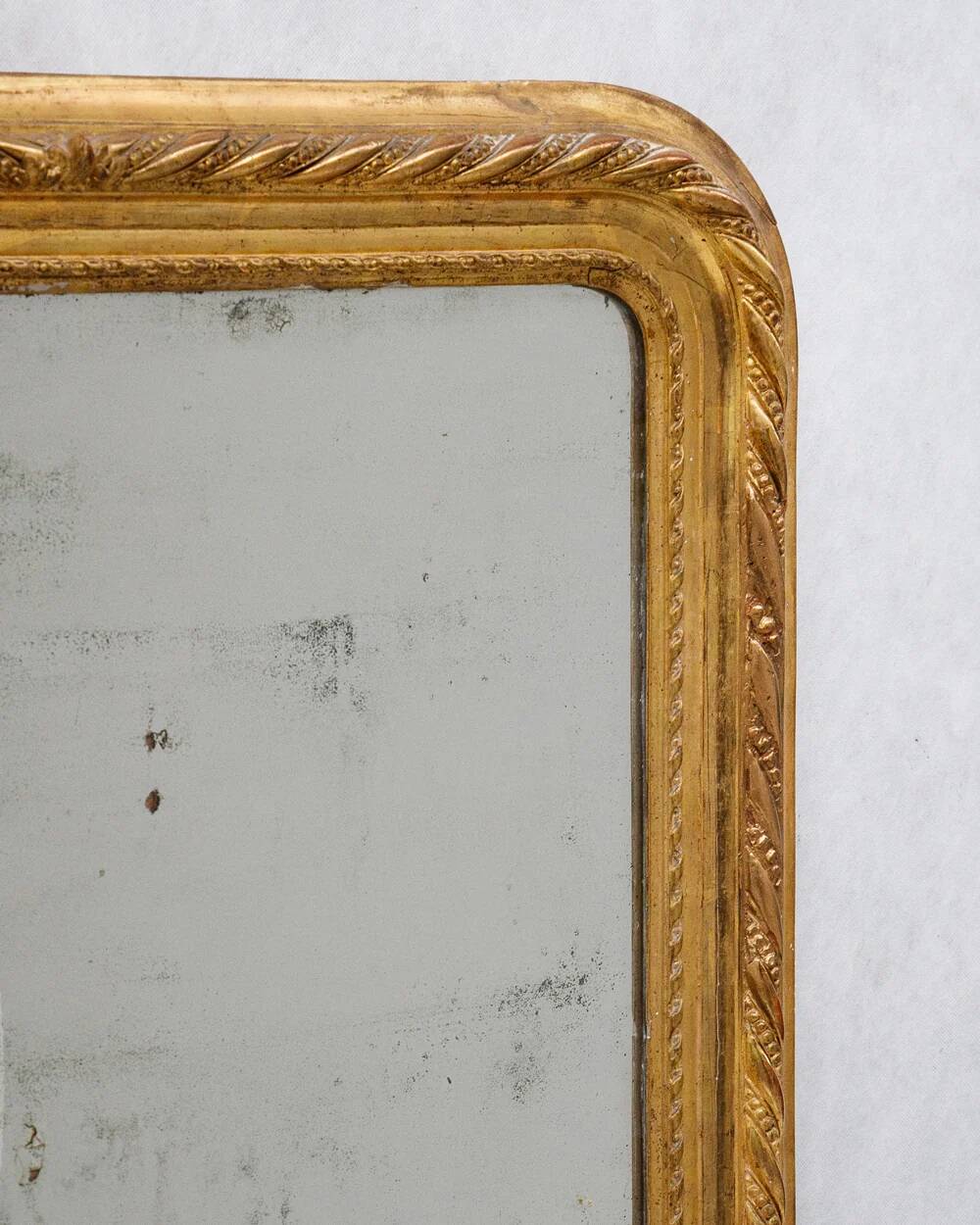 19th-century patinated mirror with a ribbon-style frame