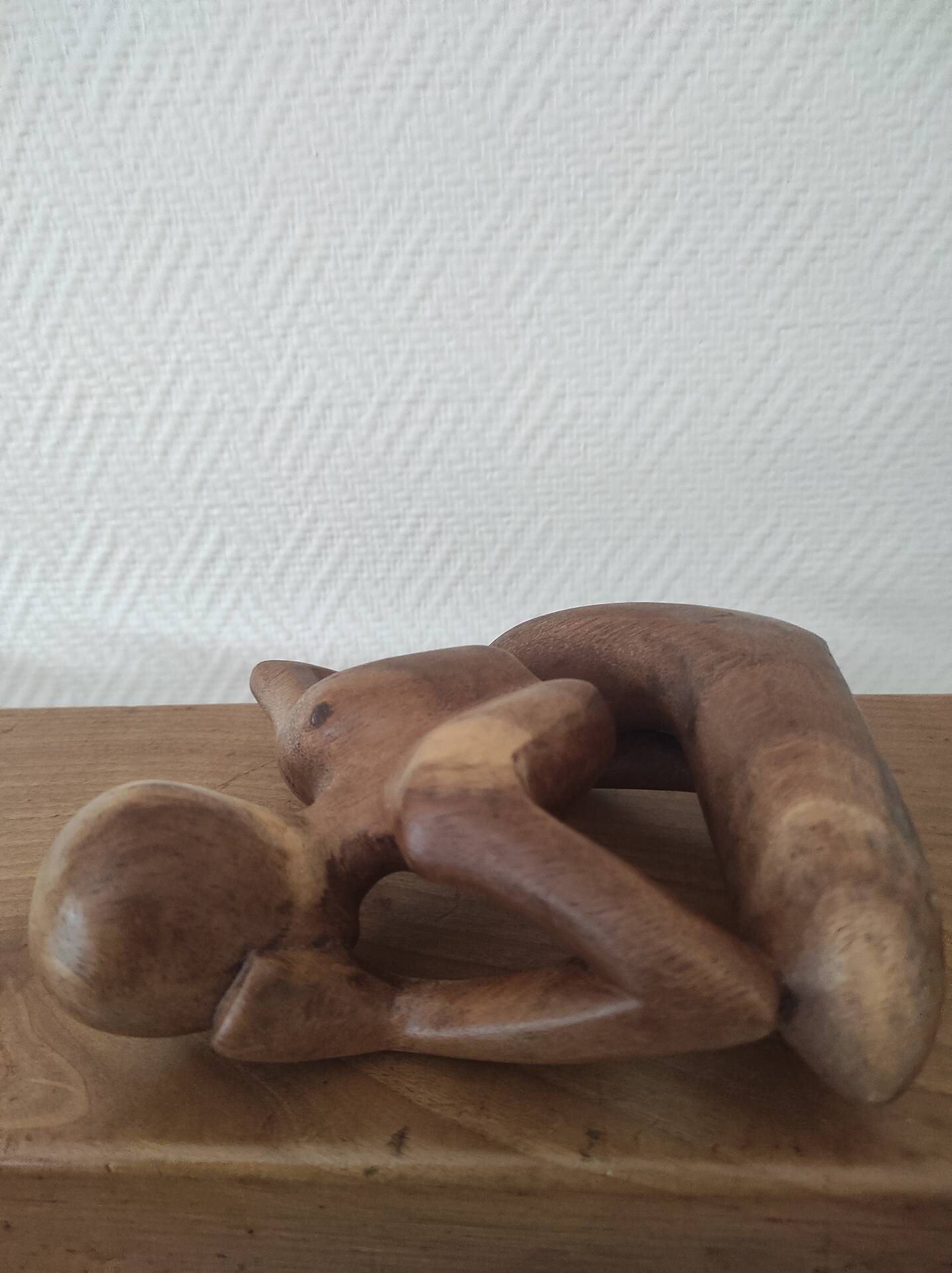 Wooden sculpted statuette of a woman in a pensive pose.