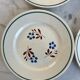 Set of 4 small flat plates with floral designs.