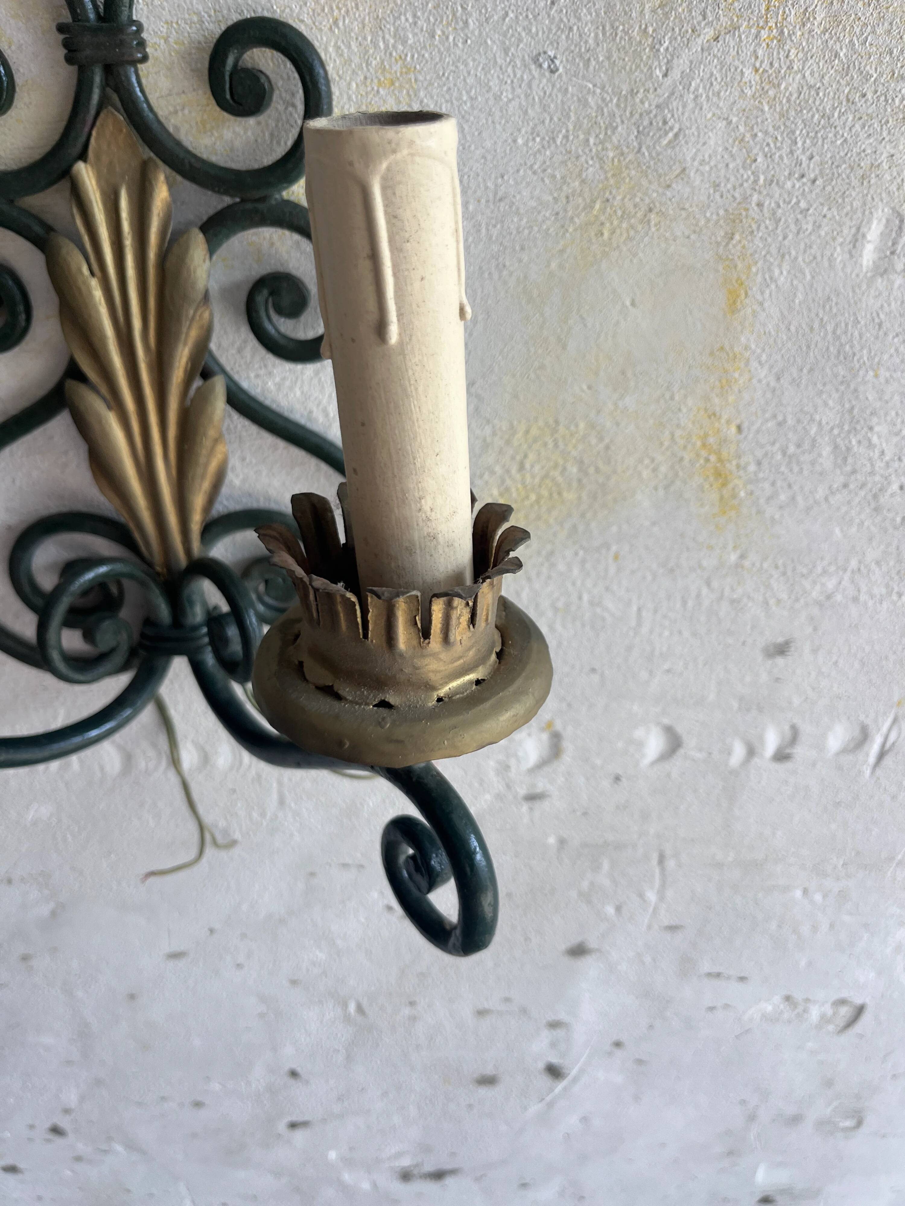 Pair of wall sconces in wrought iron with golden leaf patterns.