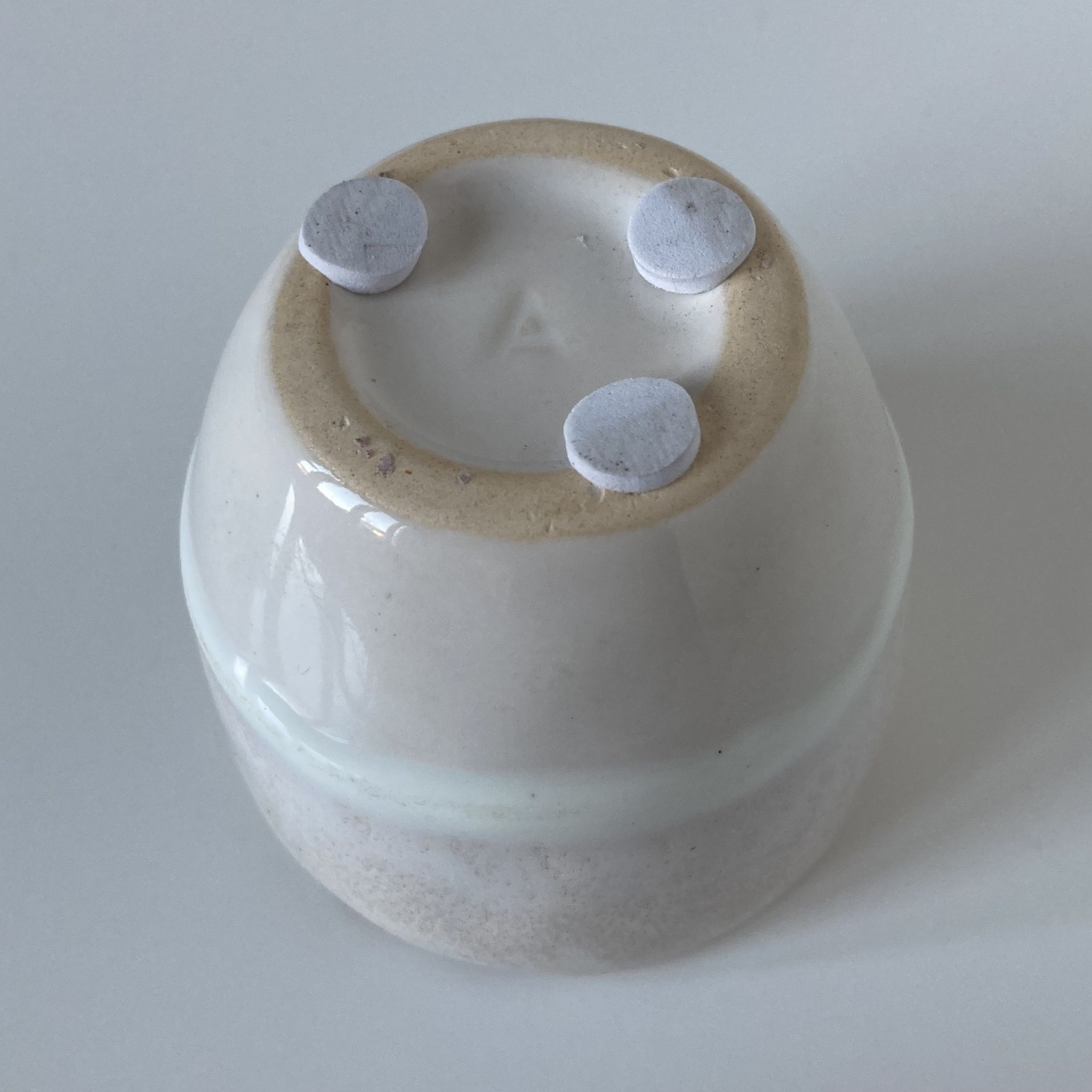 Meeting of three artist's ceramic objects including two pots and a cream covered bowl