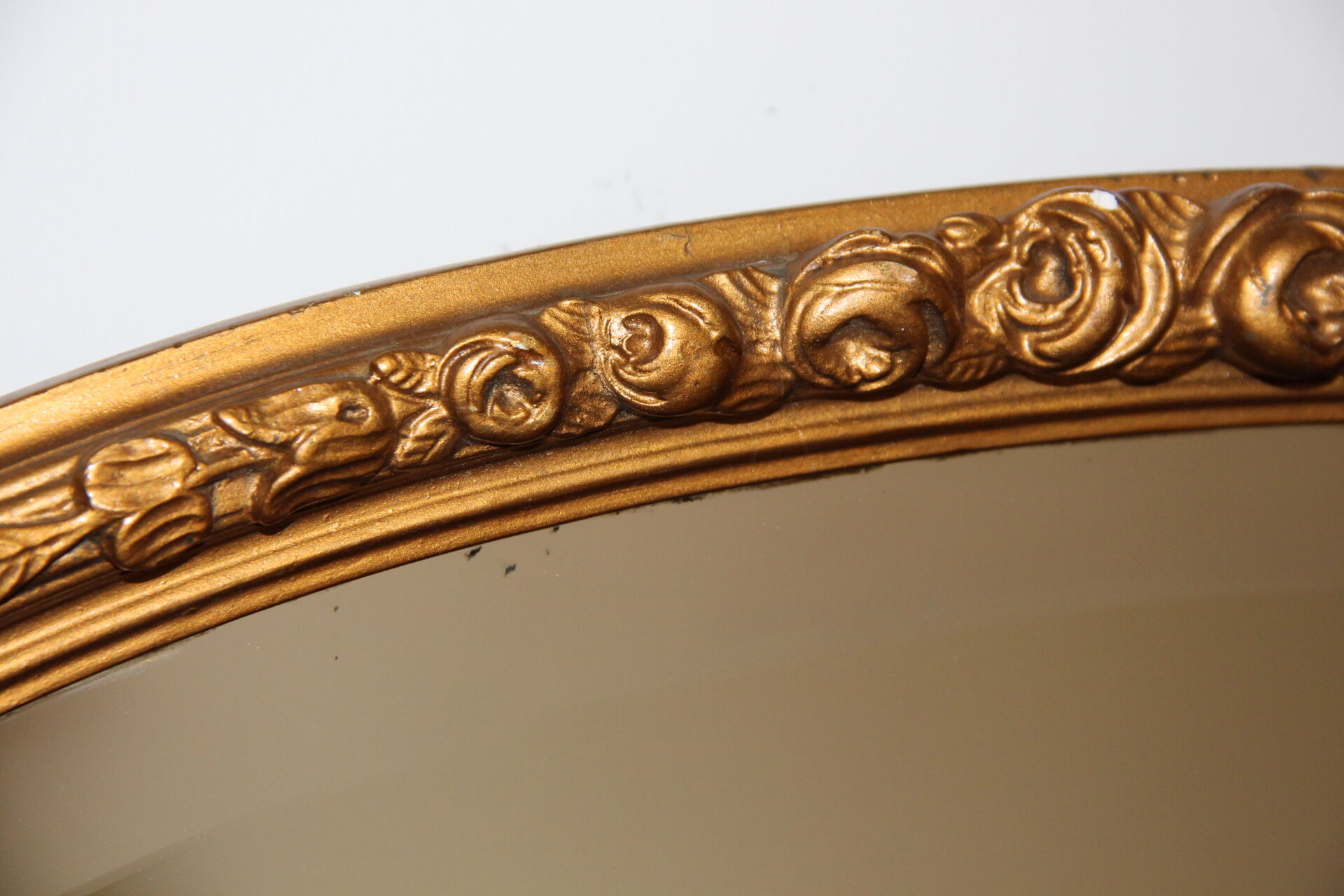 Beveled oval mirror in gilded wood