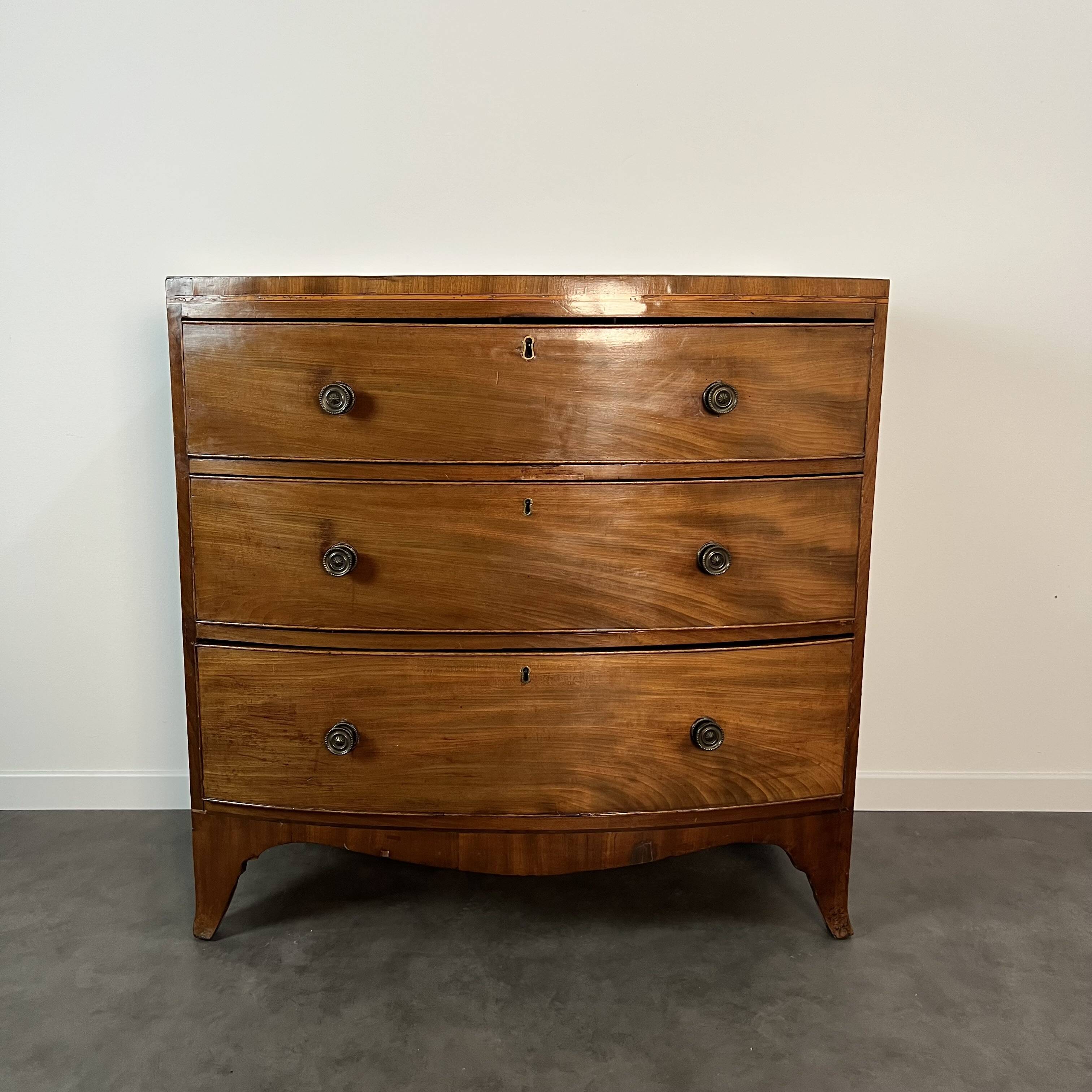 English commode from the George III Regency period, bombe shape in mahogany veneer.
