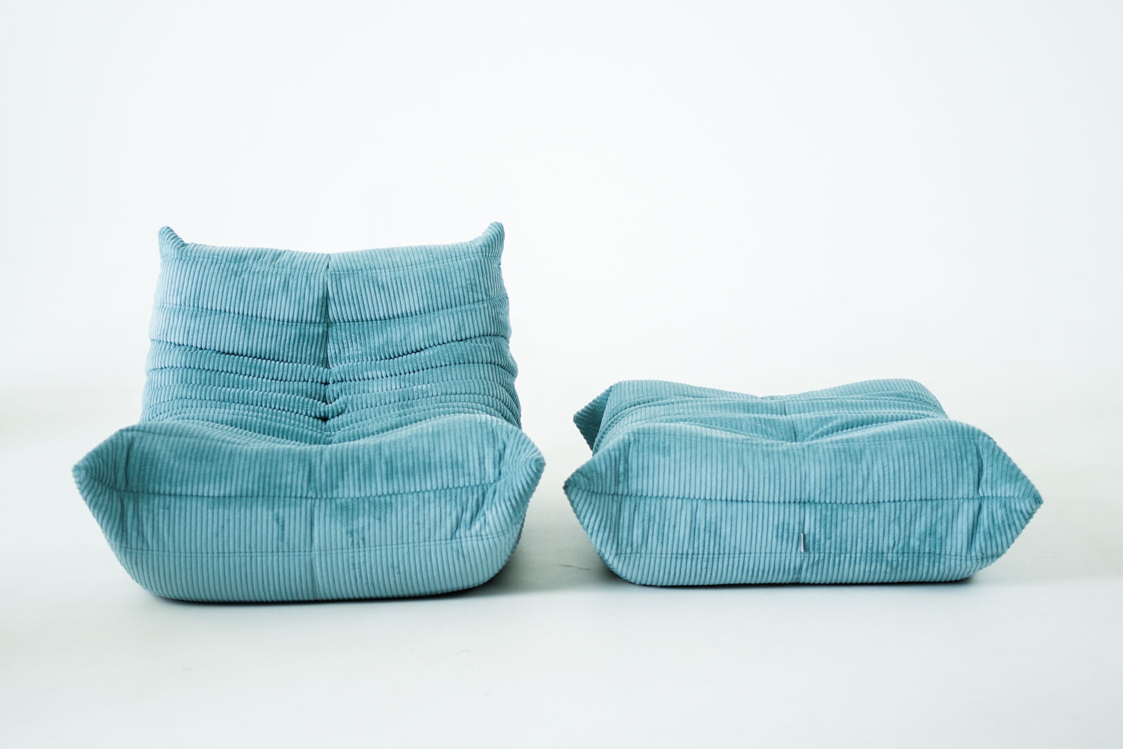 Ensemble de fauteuil et pouf Togo en velours côtelé bleu clair.