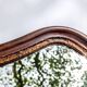 Antique wall mirror in carved wood with a wavy shape and a golden trim.