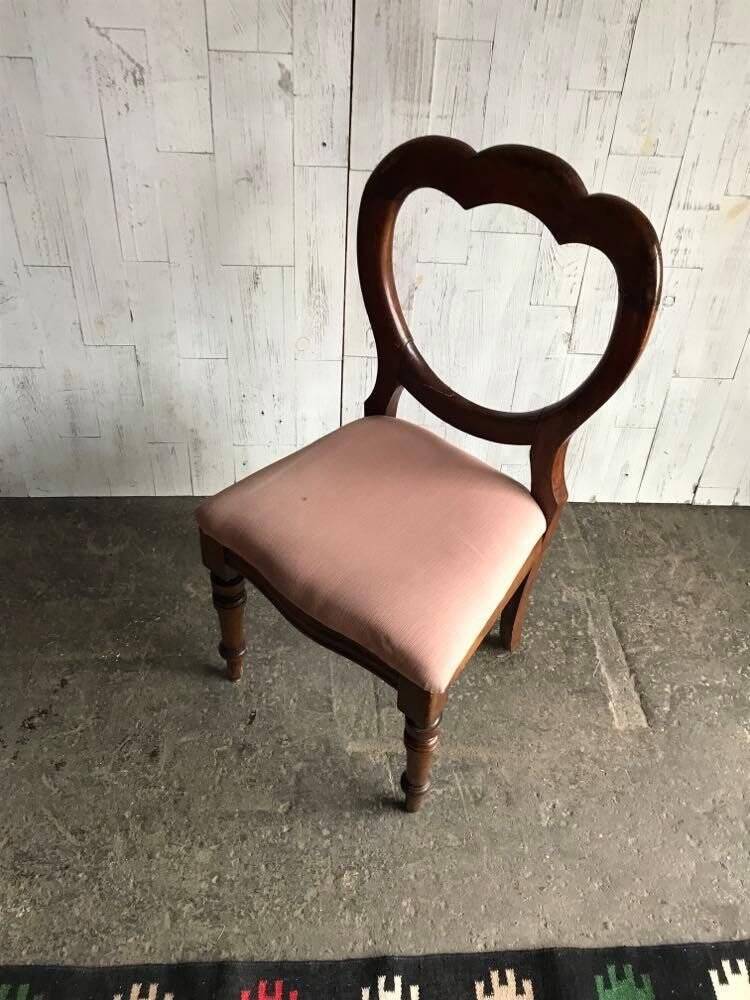 Fauteuil ancien en tissu rose et bois, dossier ajouré en cœur, pieds tournés