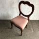 Fauteuil ancien en tissu rose et bois, dossier ajouré en cœur, pieds tournés