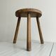 Small antique tripod stool in light wood, half-moon seat.