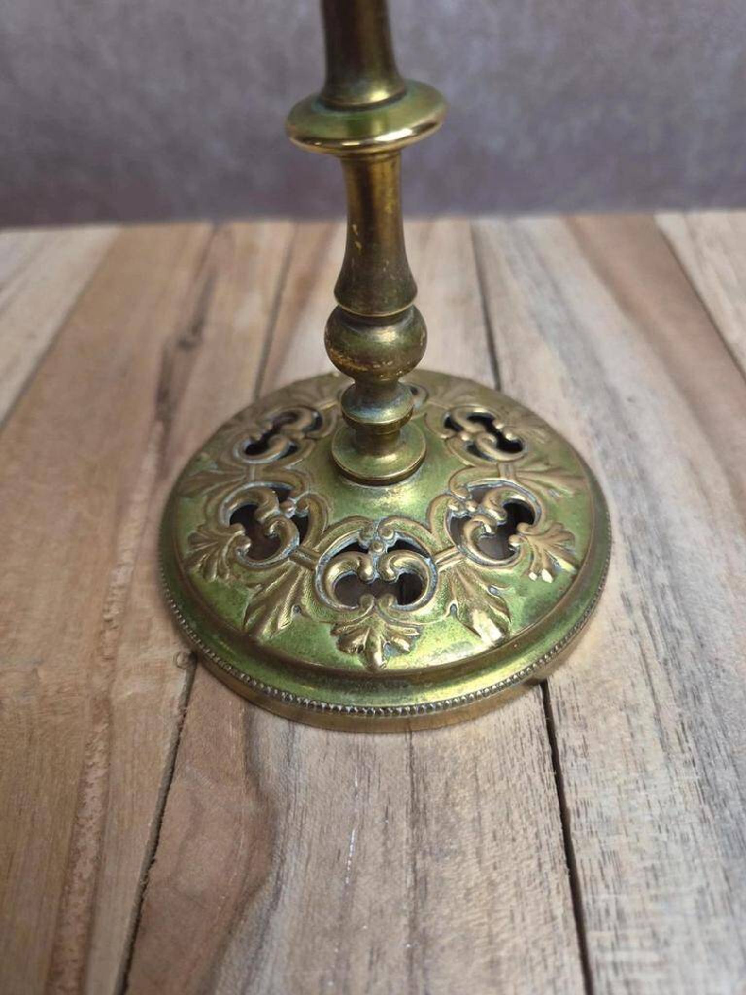 Antique brass candlestick with patina, openwork vintage foliage decoration.