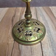 Antique brass candlestick with patina, openwork vintage foliage decoration.