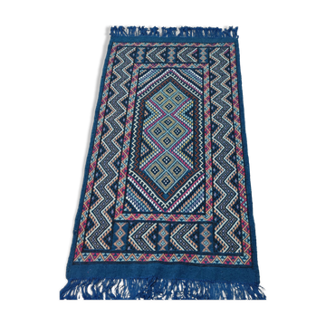 Blue carpet with multicolored patterns woven hands in natural wool