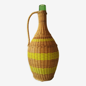 Vintage glass bottle covered with hand-woven wicker and scoubidou, with a handle