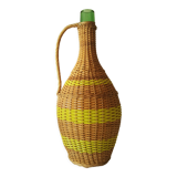 Vintage glass bottle covered with hand-woven wicker and scoubidou, with a handle