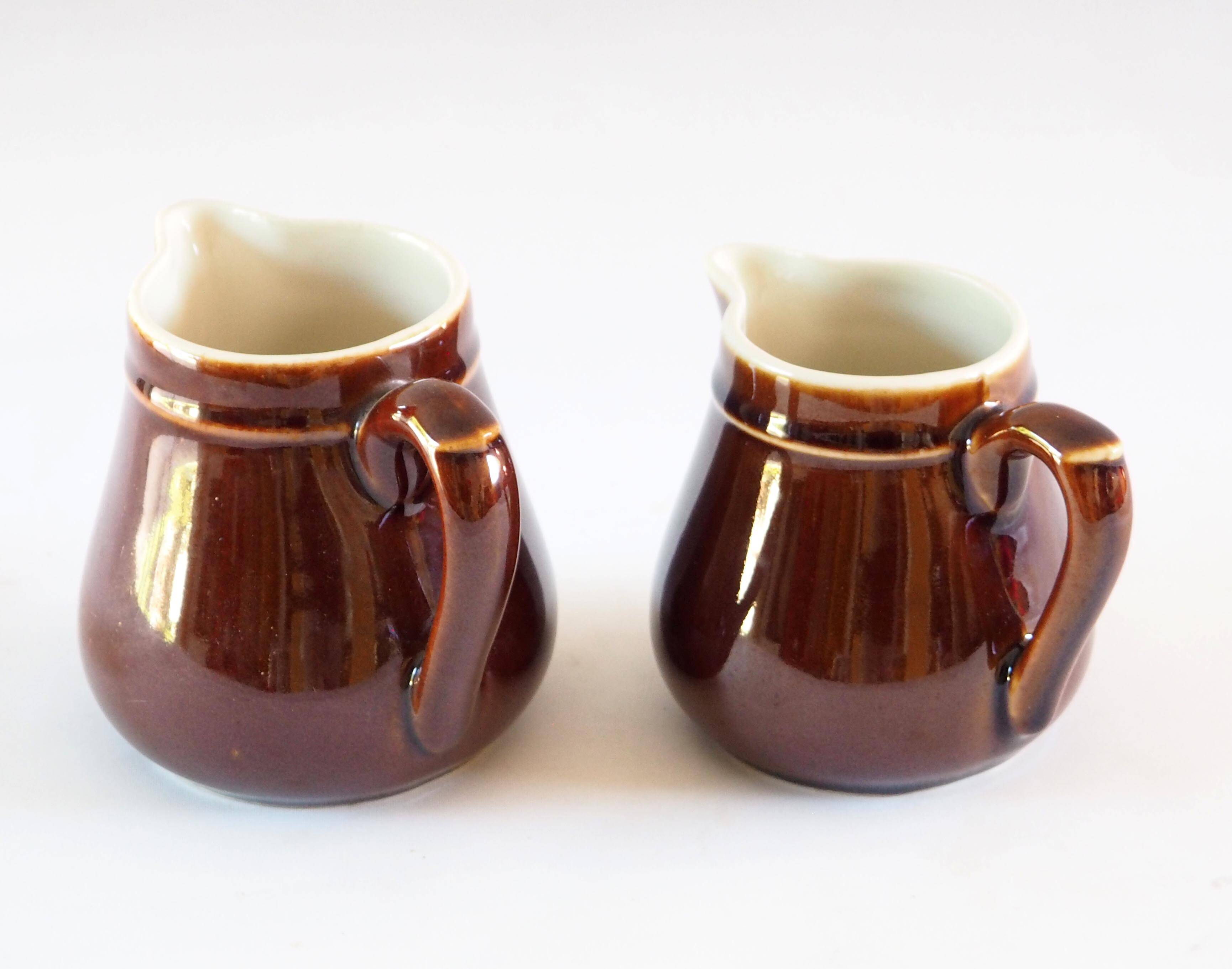 Duo of brown enamel pitchers