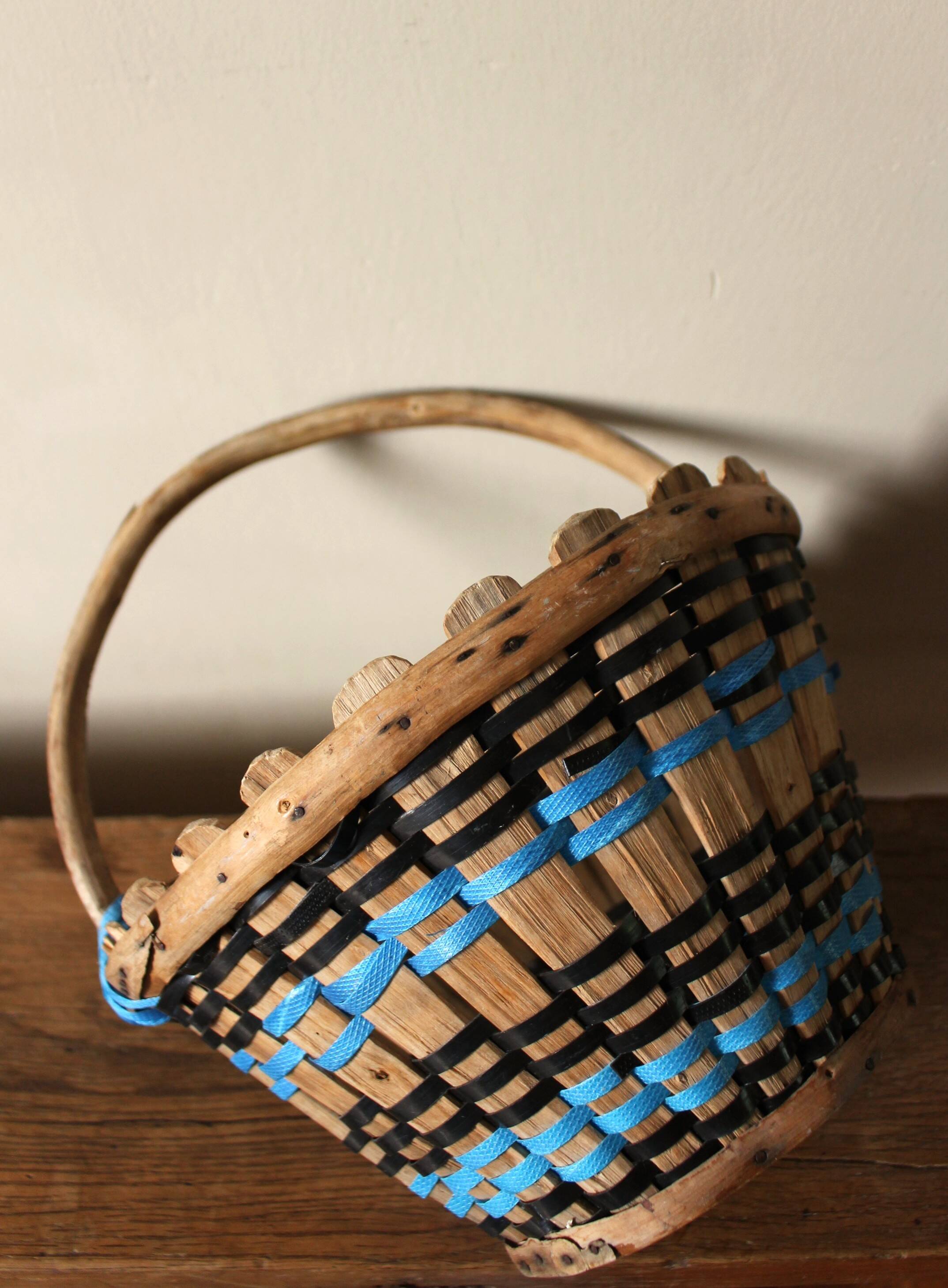 Vintage wooden basket with round handle, blue and black weaving.