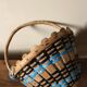 Vintage wooden basket with round handle, blue and black weaving.