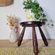Small brutalist tripod stool made of turned wood.