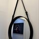 Round mirror covered in black leather in the style of Jacques Adnet.