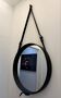 Round mirror covered in black leather in the style of Jacques Adnet.