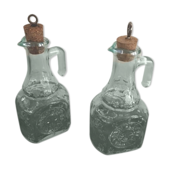Two glass bottles with a handle with turquoise reflections.