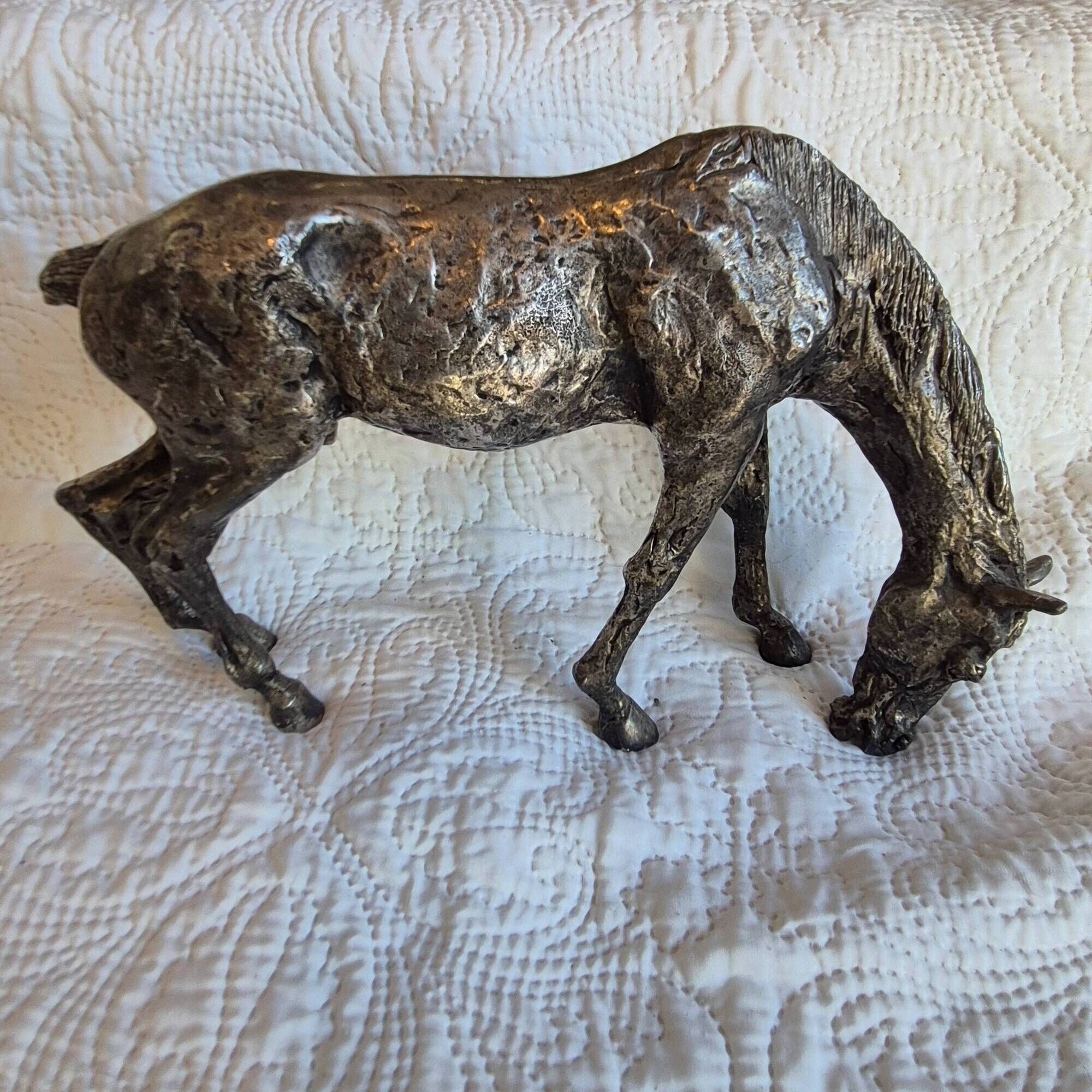 Sculpture of a grazing horse with a silver finish.