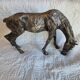 Sculpture of a grazing horse with a silver finish.