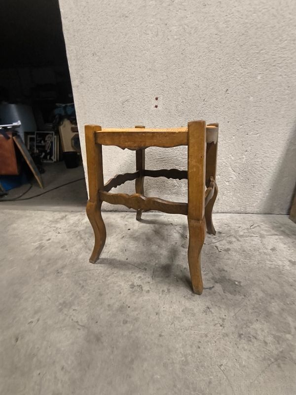 Rustic wooden stool with a straw seat.