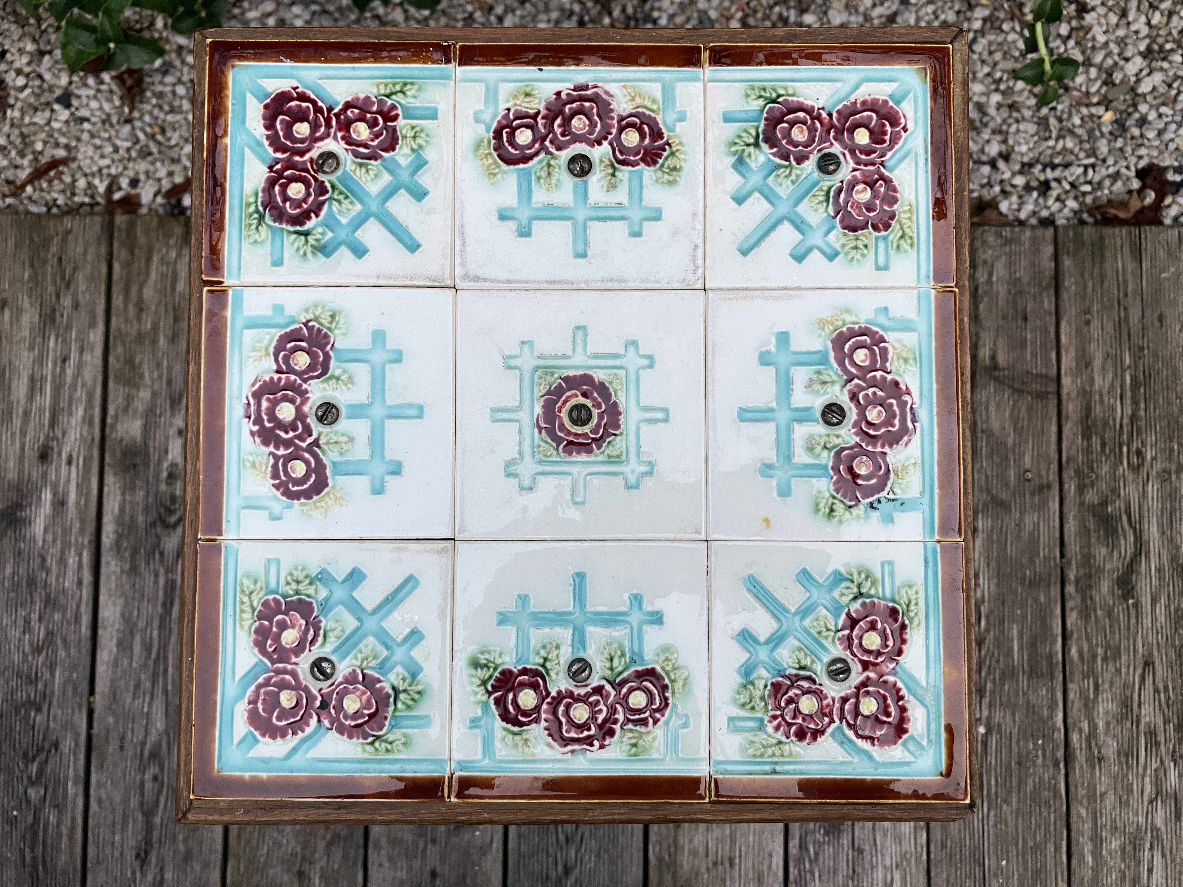 Antique wooden plant stand with ceramic tiles.