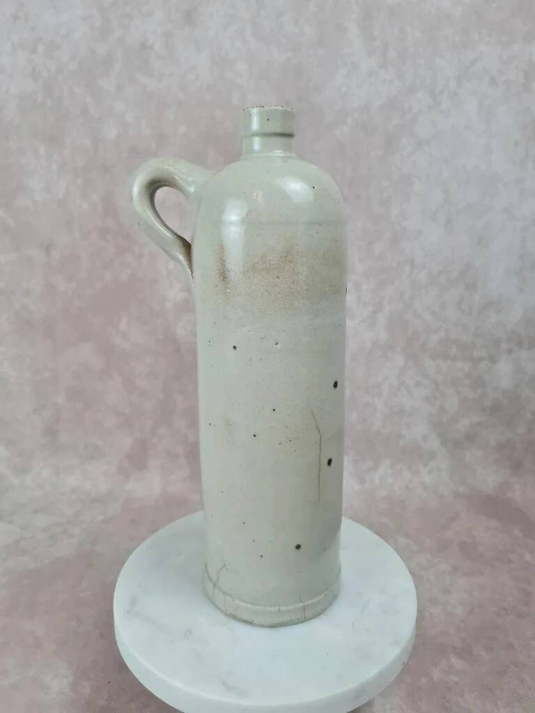 Antique beige glazed stoneware bottle from the 19th century, with a handle, vintage decor.