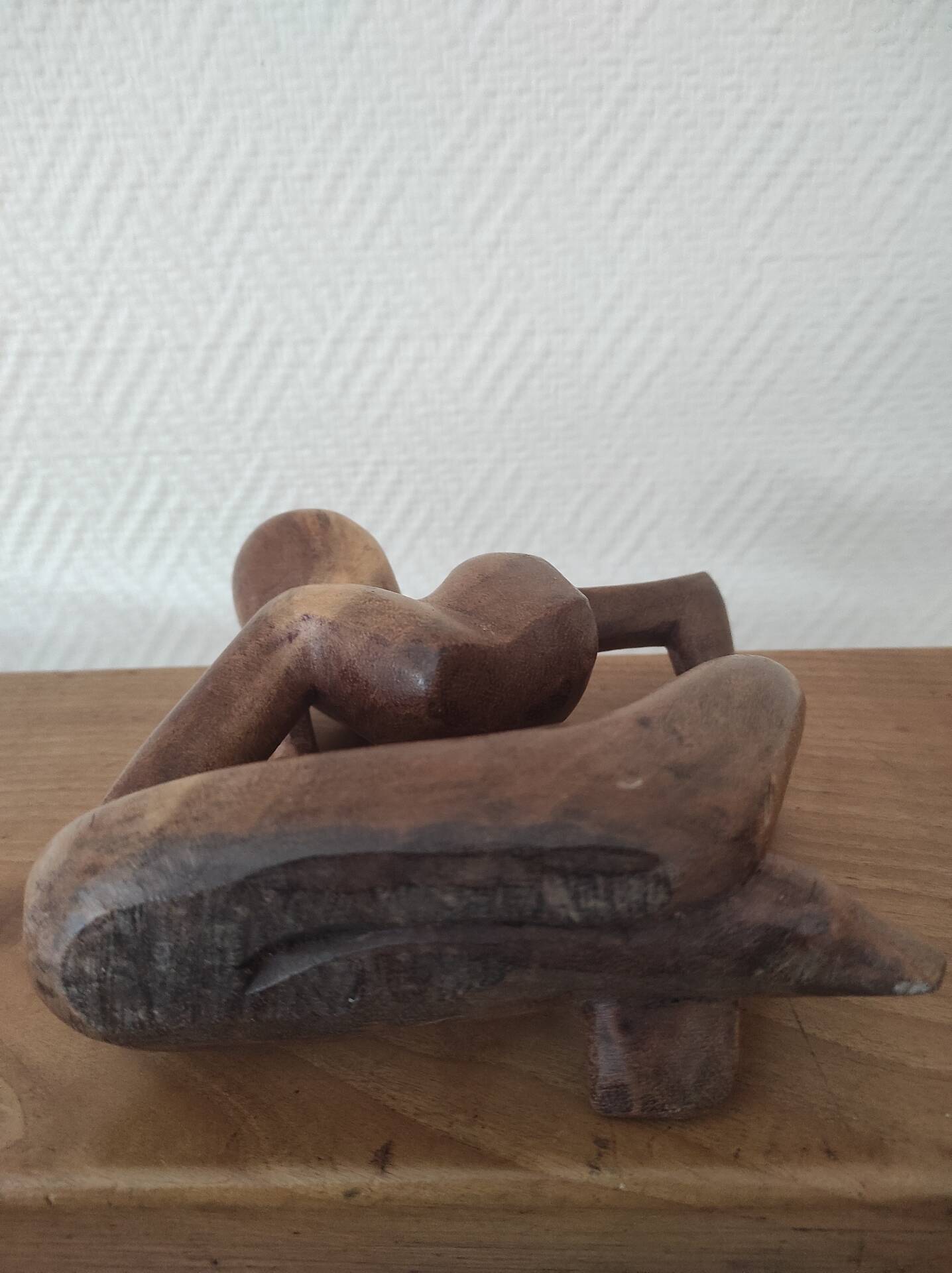 Wooden sculpted statuette of a woman in a pensive pose.