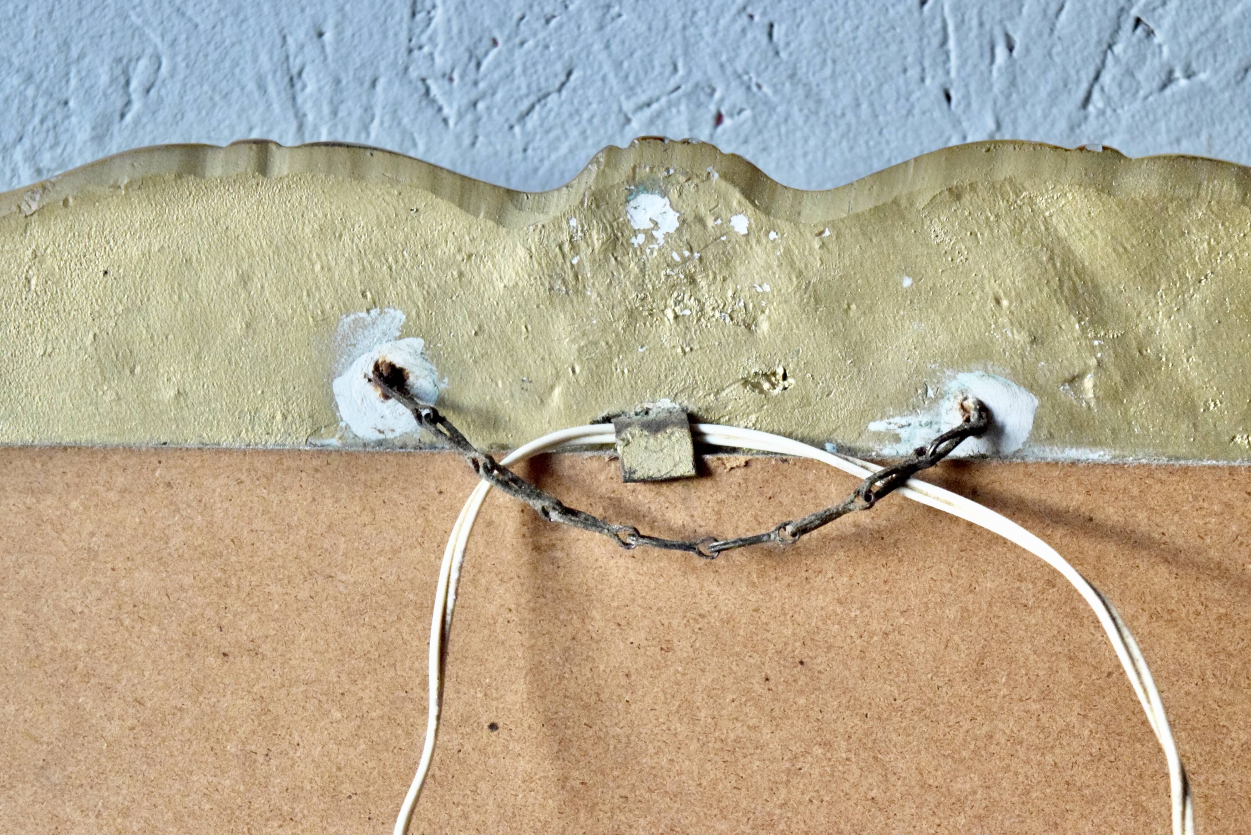 Old religious light frame in gilded stucco and curved glass