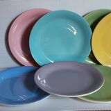 Seven pastel-colored plates mixed with vintage earthenware