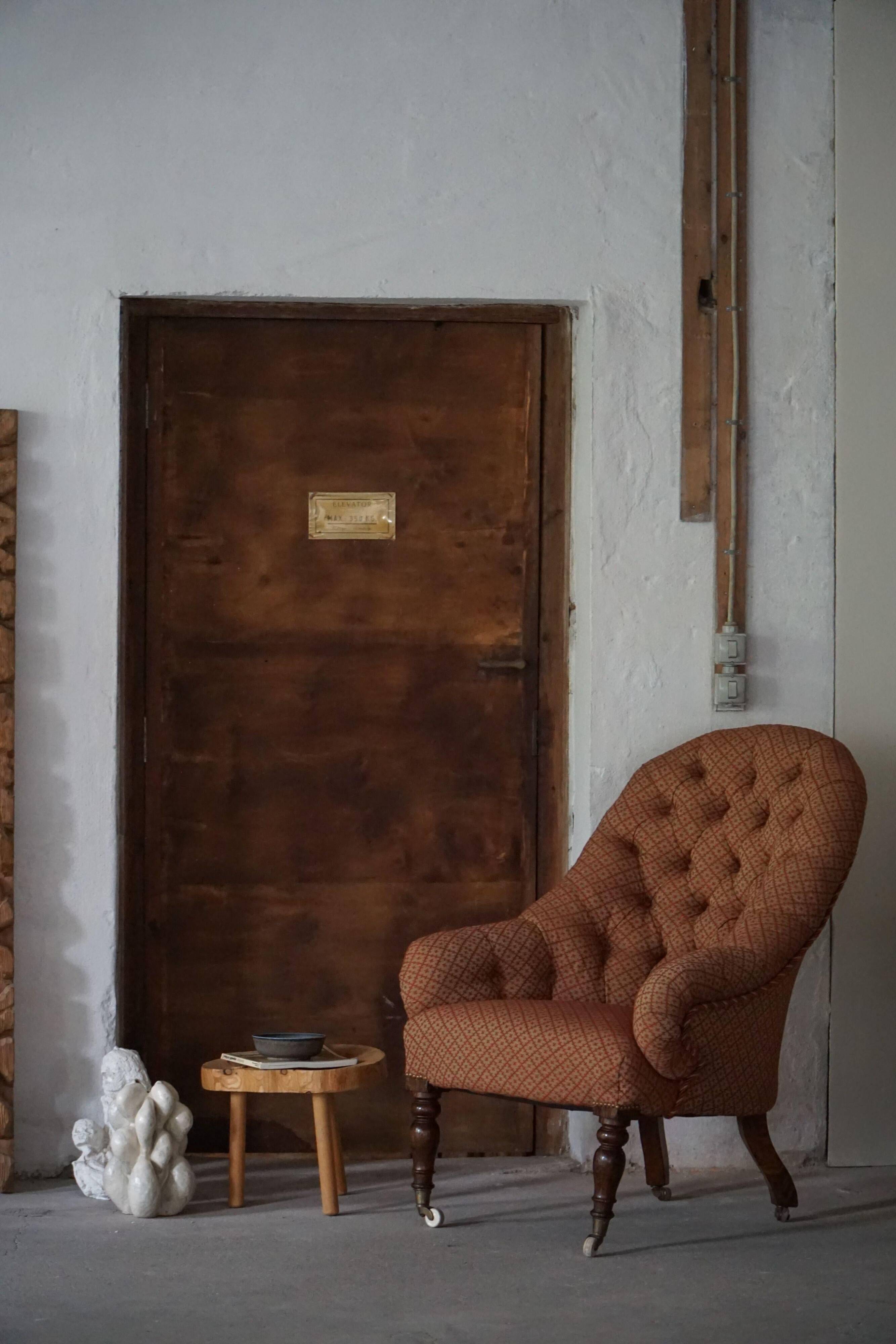 Victorian mahogany armchair, with wheels and coloured fabric, England, early 1900s.