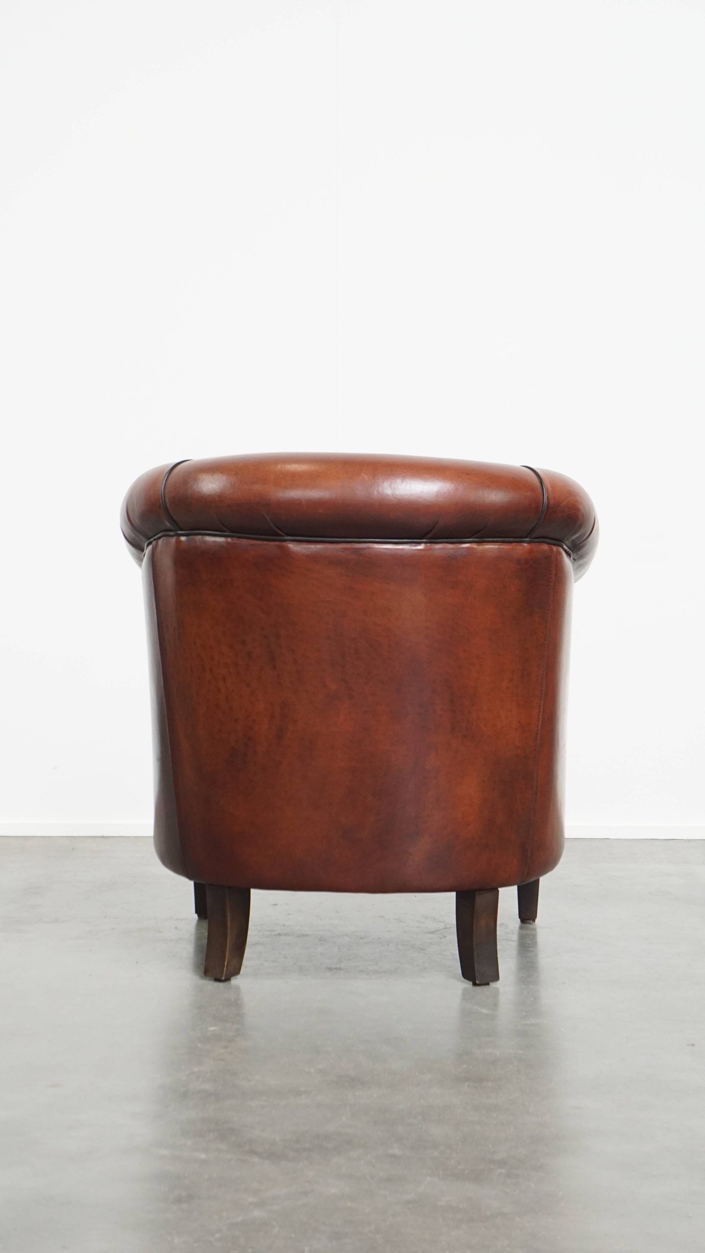 Sheepskin club armchair in a warm deep colour finished with black piping