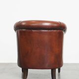 Sheepskin club armchair in a warm deep colour finished with black piping