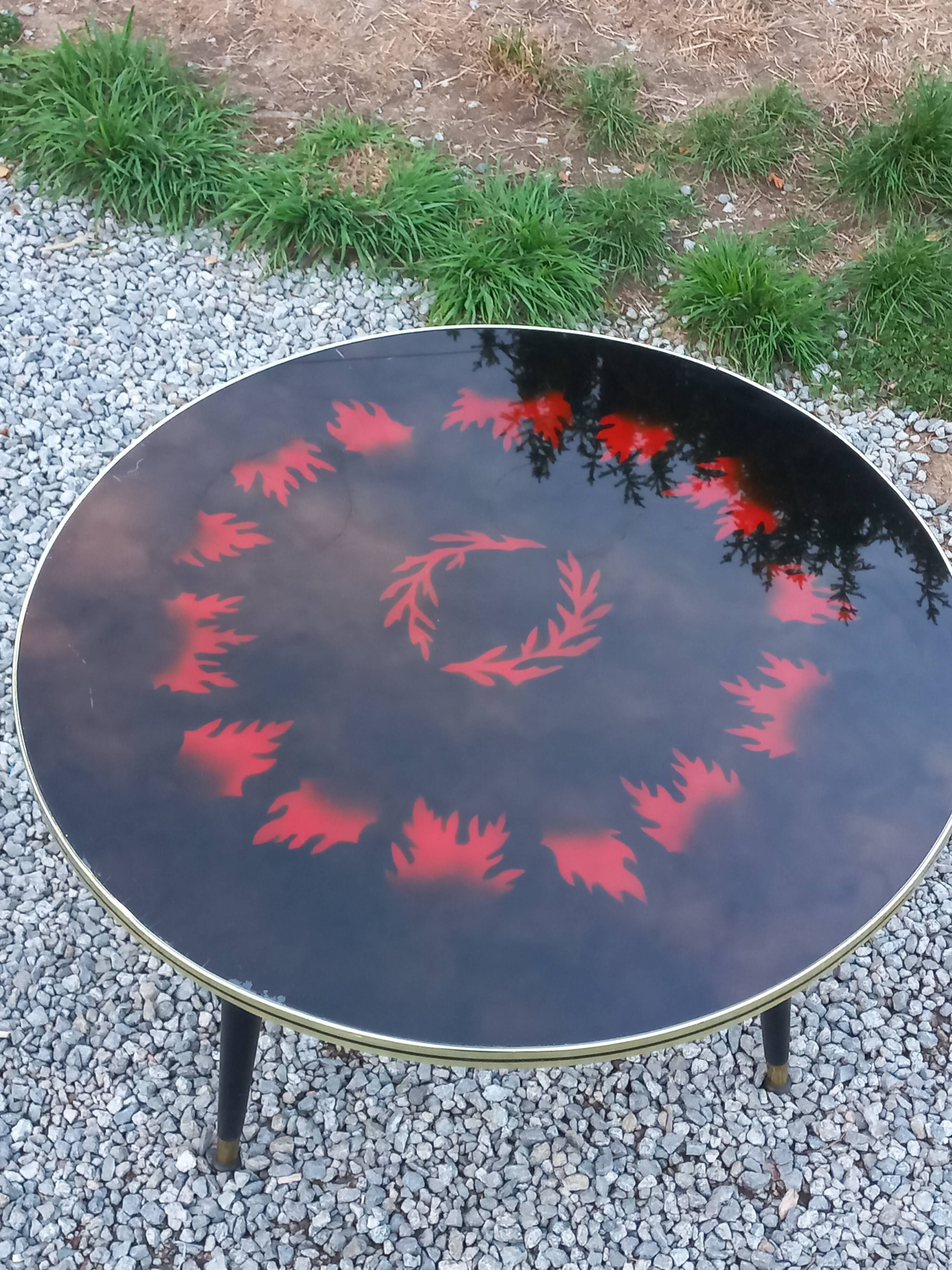 Vintage coffee table with glass top and tripod legs in blackened wood from the 1960s.