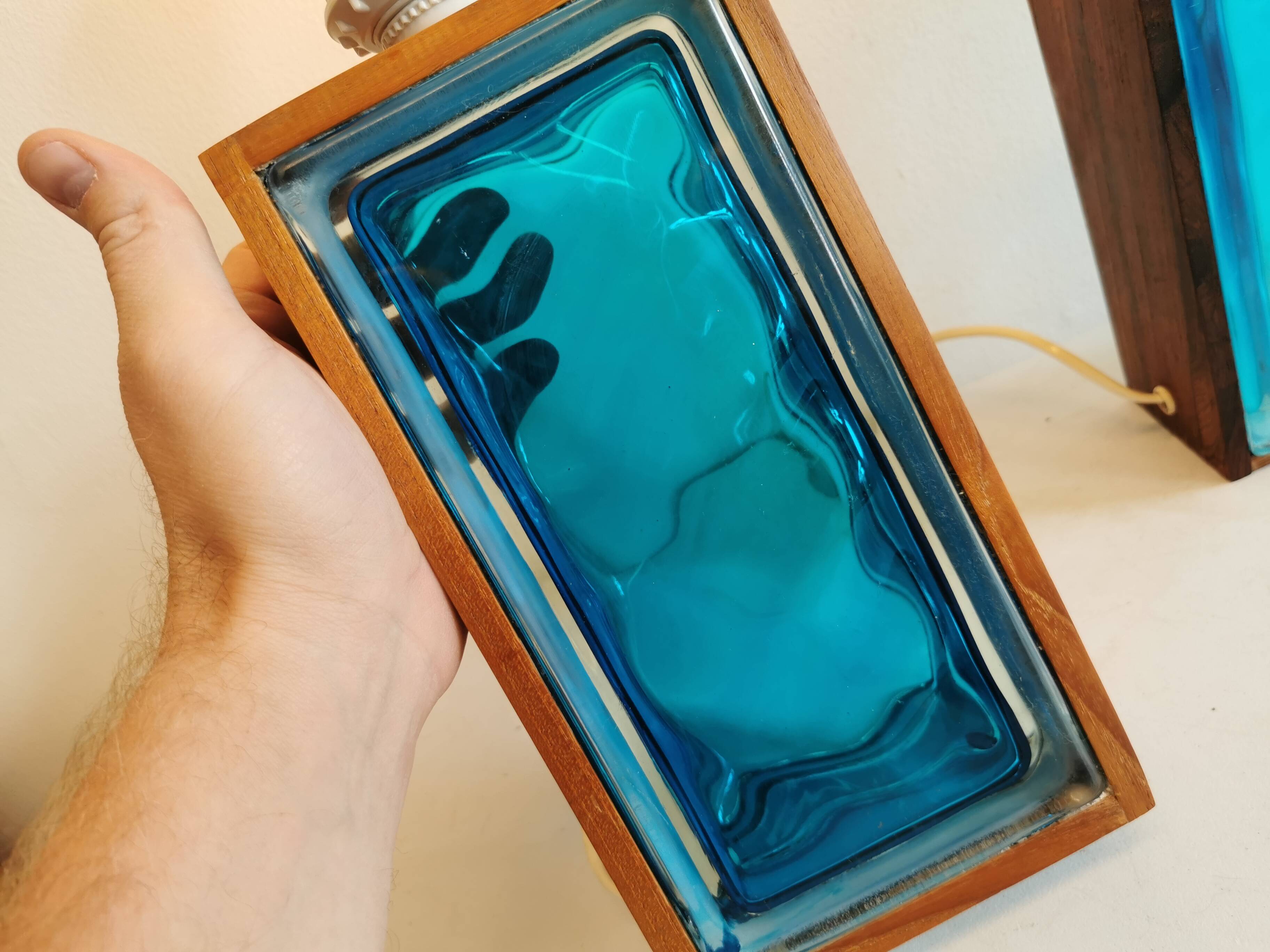 Two Swedish table lamps in solid pressed blue glass and teak wood "frame".
