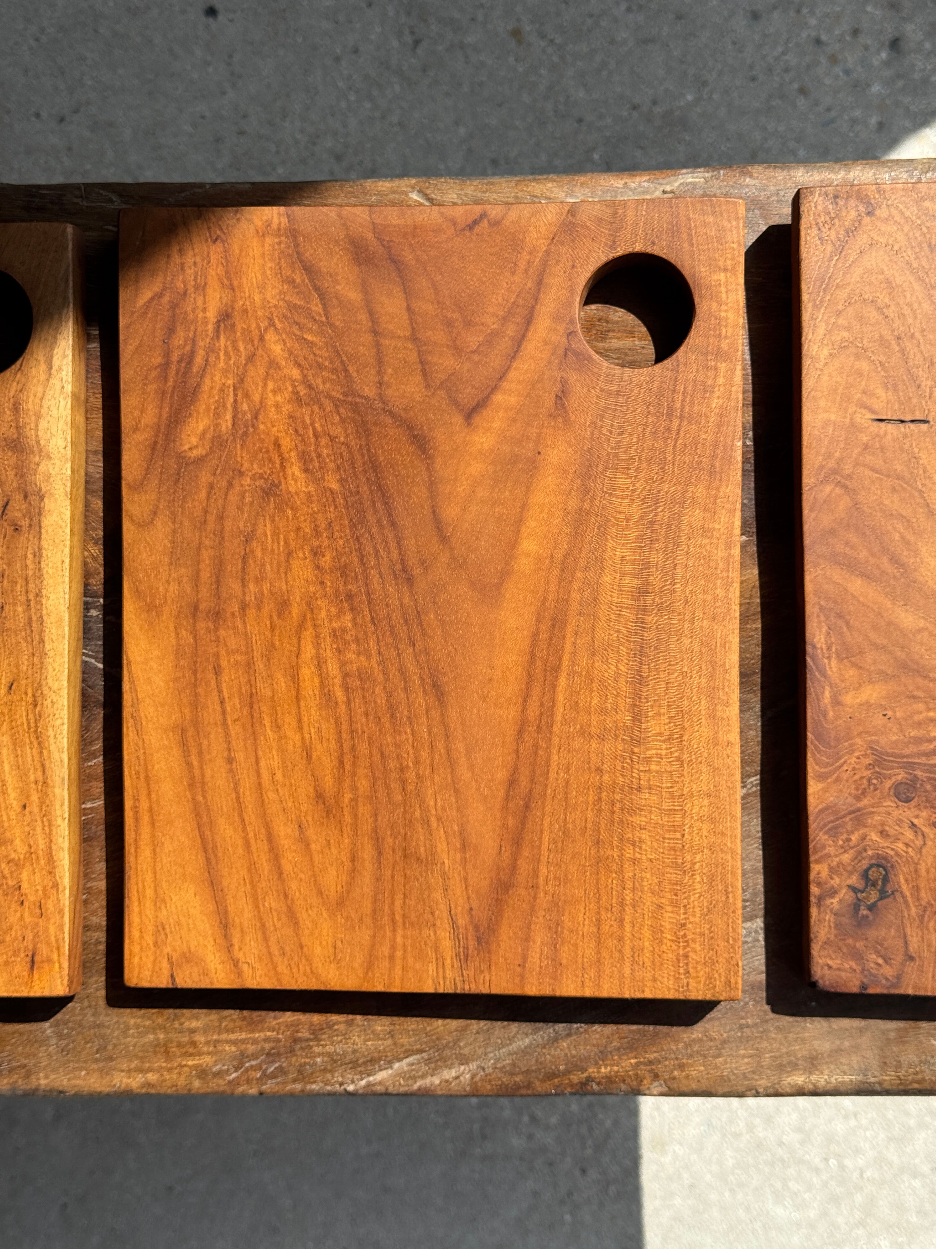 Small rectangular teak monoxyle cutting board with a circular handle.