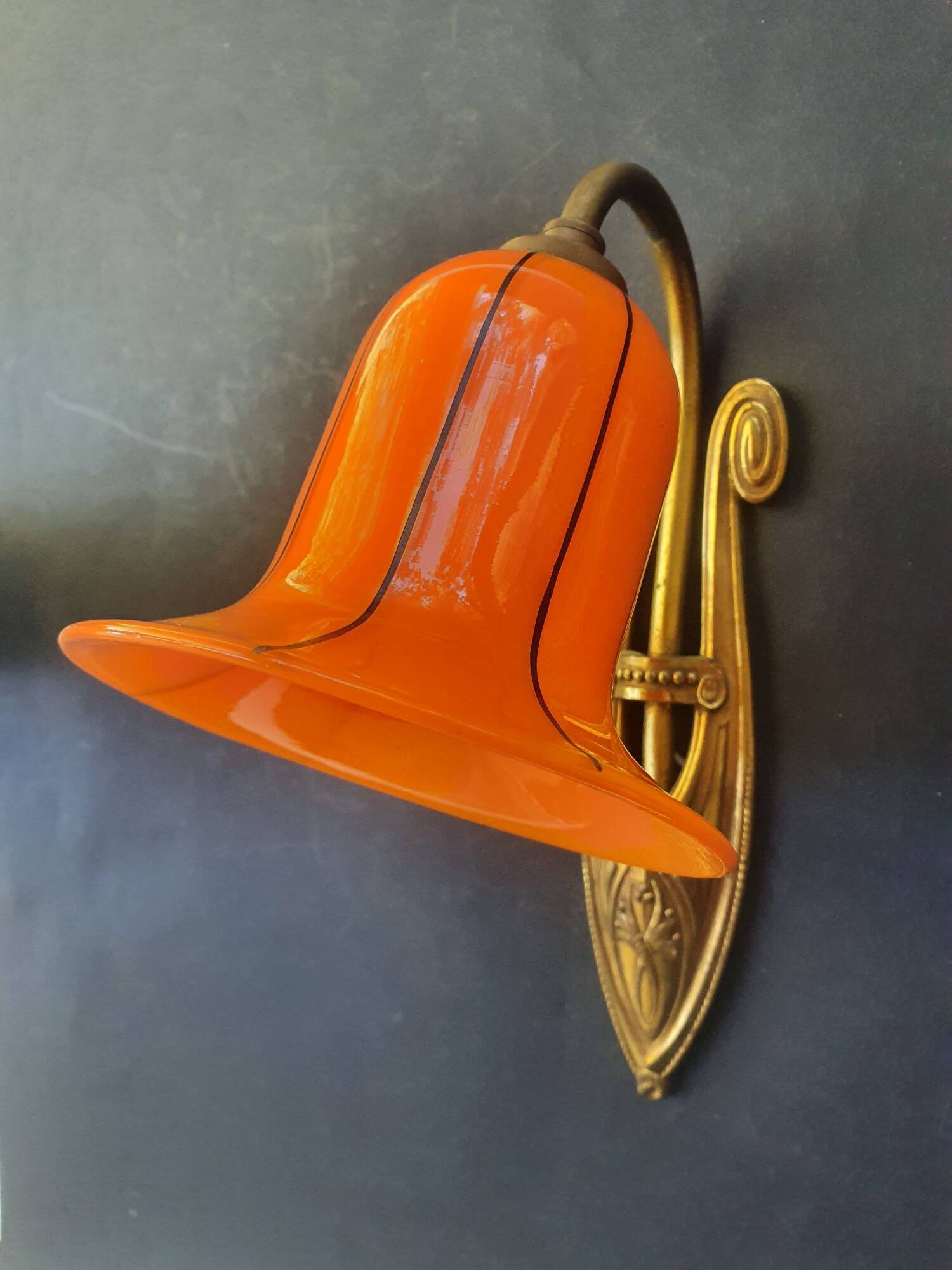 Art Deco wall light in brass with an orange globe.