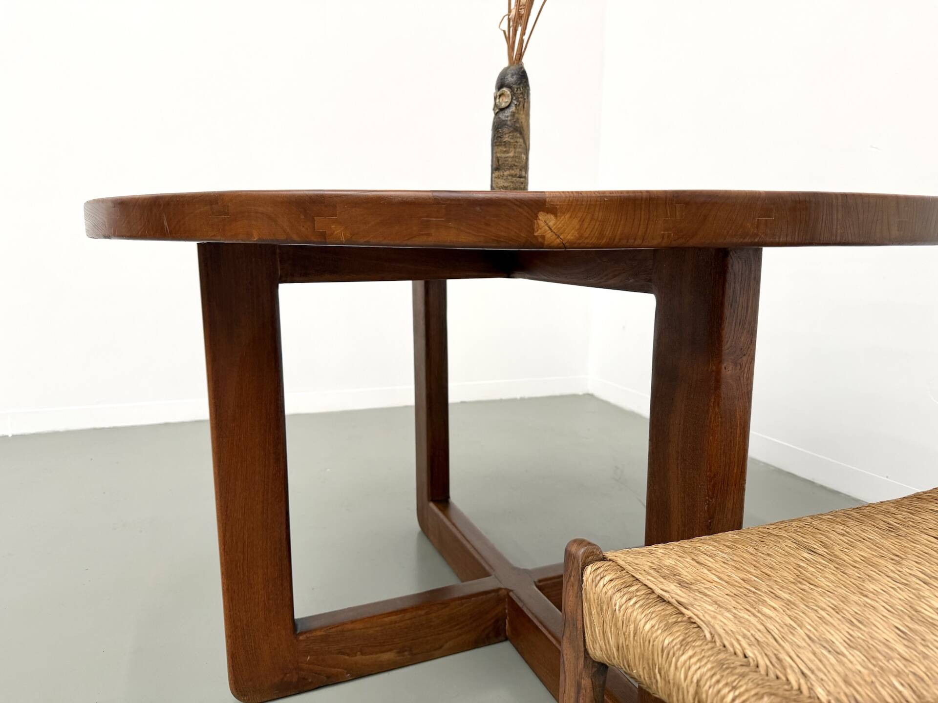 Modernist round table in solid elm, crossed legs.