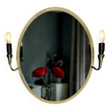 Oval wall mirror in gilded brass with double sconces – 1950s/60s