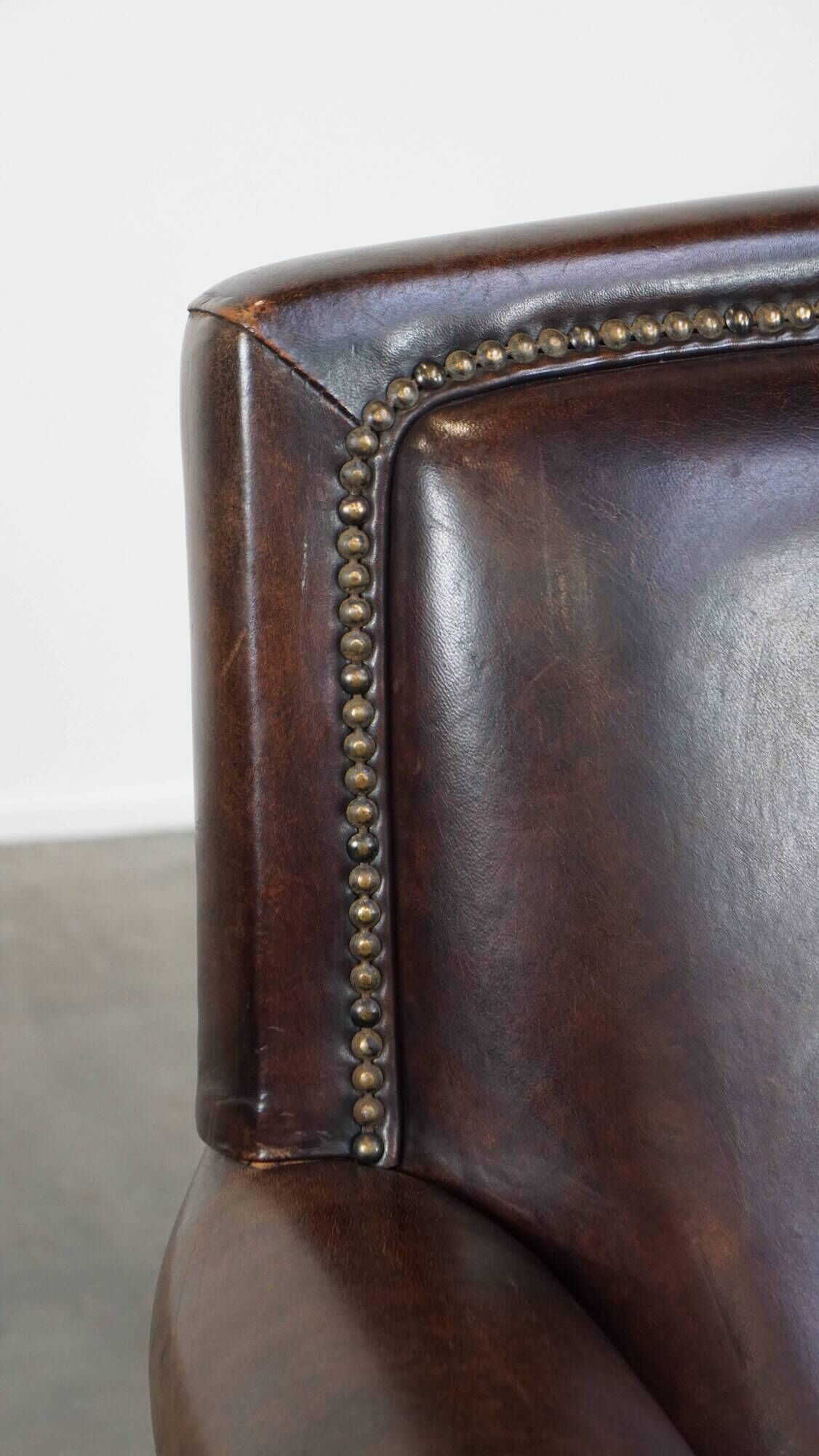 Dark brown sheepskin armchair finished with decorative nails