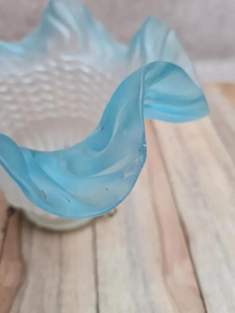 An antique lampshade in frosted glass with delicate blue edges.
