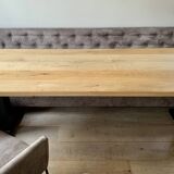 Dining table made of wood with three leather seats and a long leather sofa.