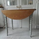 Walnut table with raised flaps, base on verdigris casters.