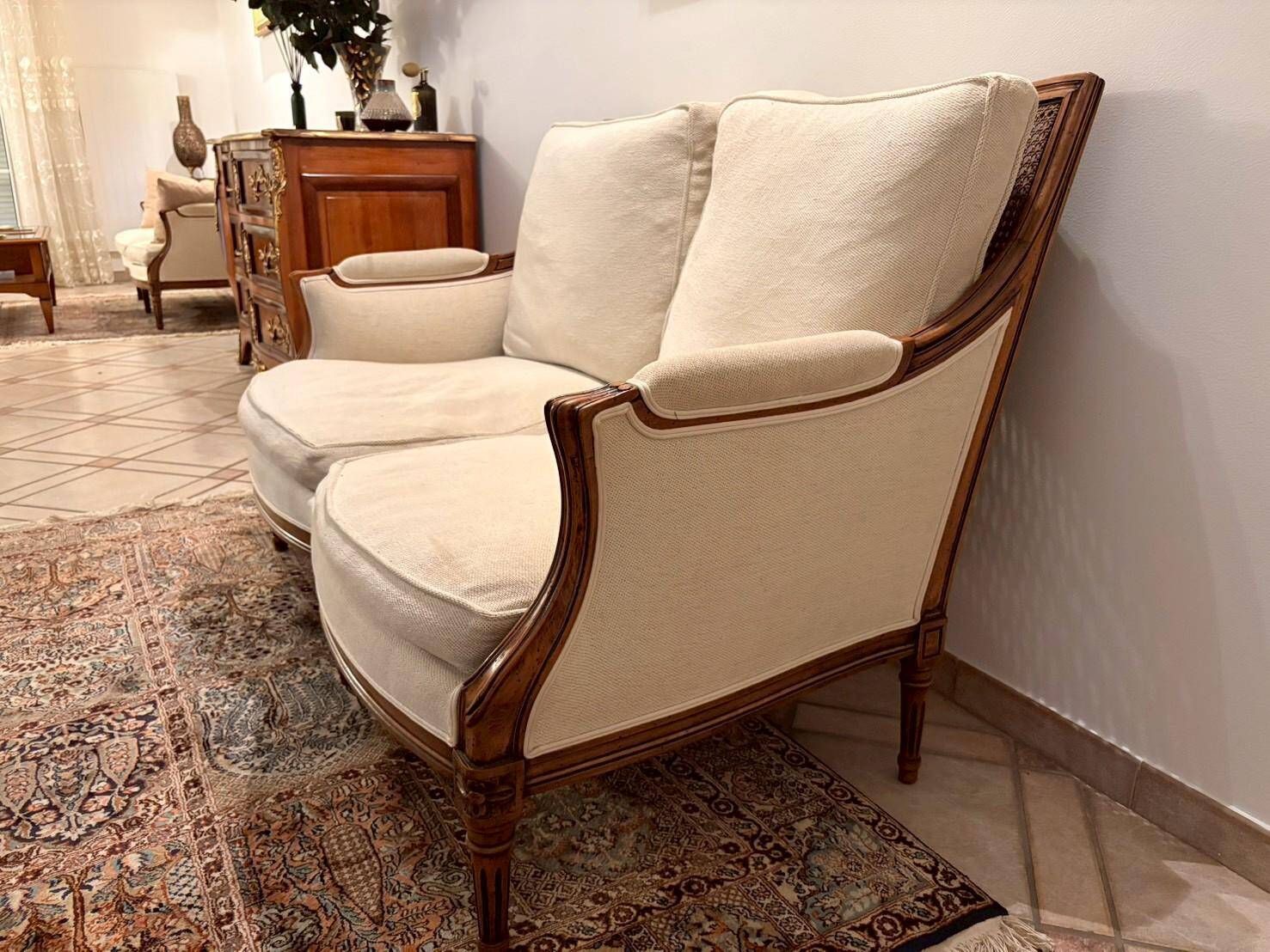 Two-seater canapé by Roche Bobois in Louis XVI style — carved wood, caned sides.