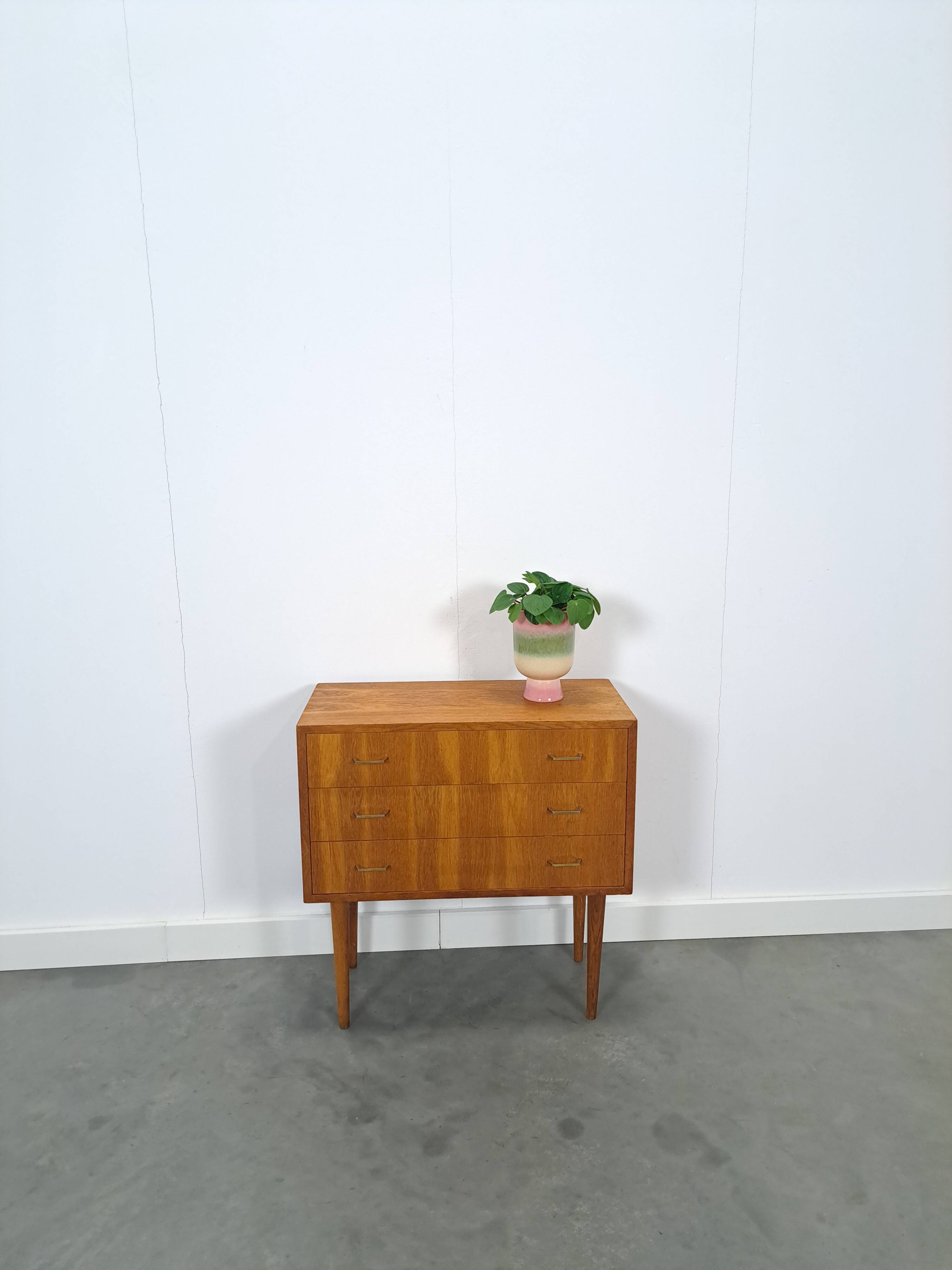 Commode danoise avec de hauts pieds et des poignées dorées.